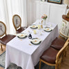A white dining table set with gold accents, featuring white linen tablecloths and dark brown leather chairs.