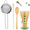 A traditional bamboo matcha tea set featuring a metal strainer, wooden spoon, and bamboo whisk in a glass container.