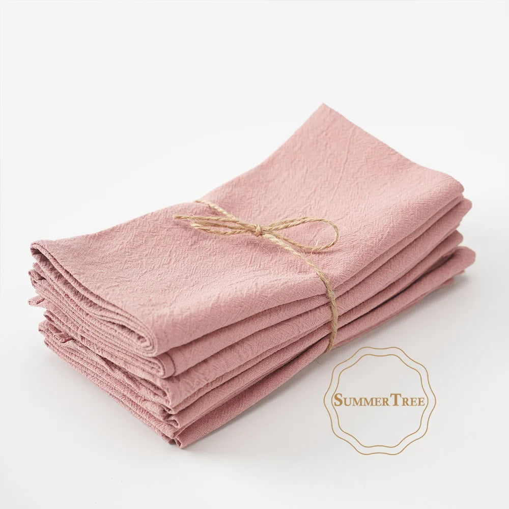 A stack of ten pink cotton table napkins tied with twine.