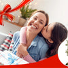 A smiling woman is affectionately kissing a young girl while holding a gift box, set against a bright indoor background.