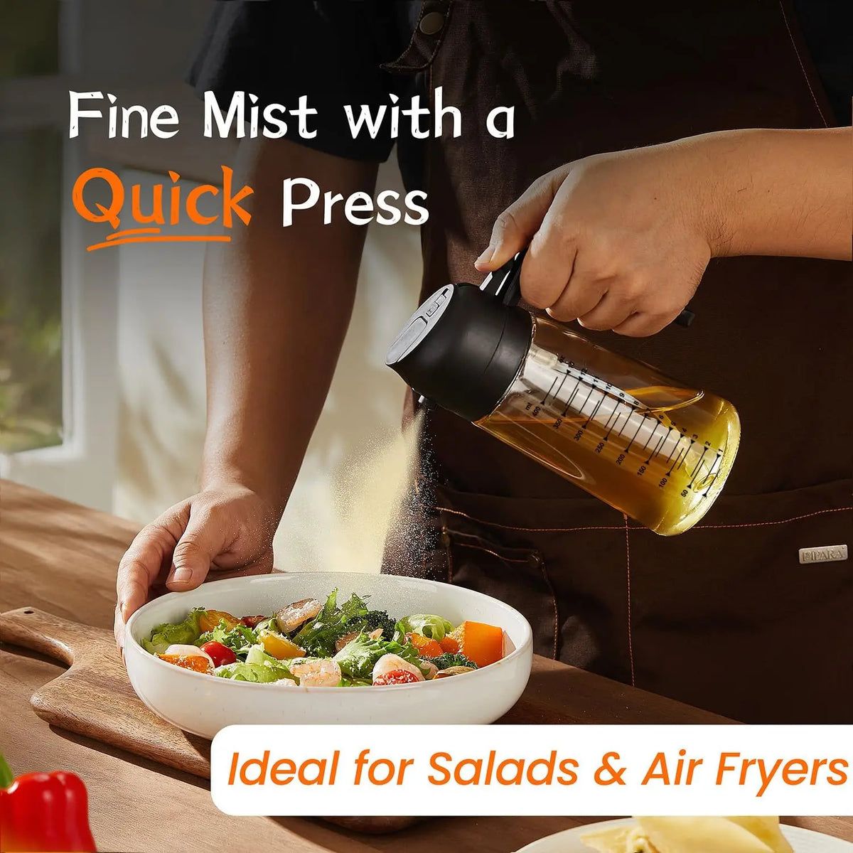 A hand is using a glass olive oil sprayer dispenser to mist food for salads and air fryers.