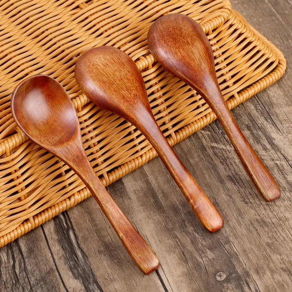 Ein Set aus drei natürlichen Holzrührlöffeln auf einer geflochtenen Bambusmatte.