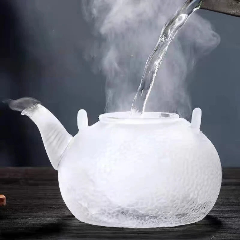 Hand-hammered glass teapot with hemp rope design pouring water into a cup