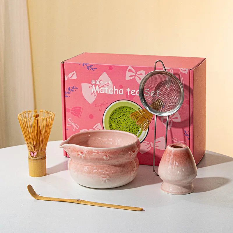 A pink box contains a Japanese matcha tea set including a ceramic bowl and a fine mesh strainer.