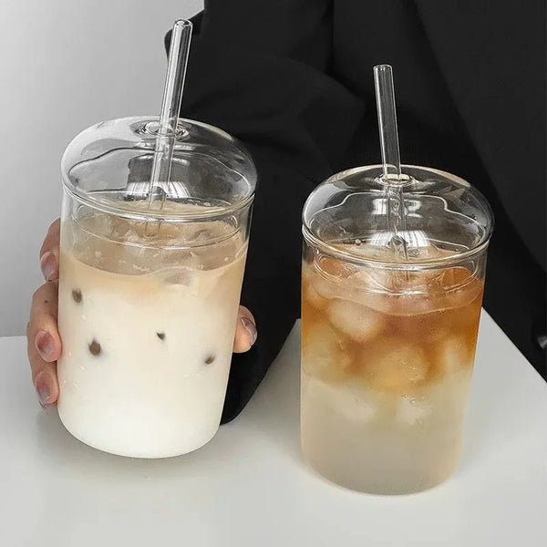 Klares Glas mit Eis-Tee oder Getränk, mit Deckel und Strohhalm, vor dunklem Hintergrund.
