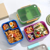 A green and yellow 3-compartment leakproof bento lunch box filled with food, including rice, shrimp, and egg.