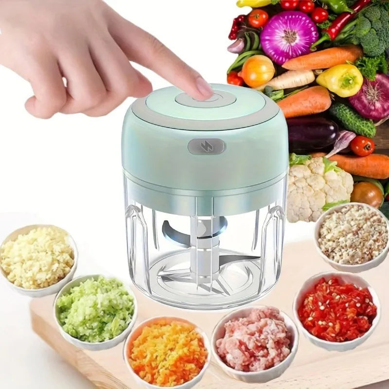 A hand is operating a clear plastic portable electric mini food chopper and grinder, showing various chopped ingredients.