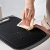 A hand is wiping a black silicone kitchen knife and tool set with a white cloth.