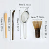A set of four bamboo tea whisk tools, including a wooden spoon, a long stick, a metal strainer, and a bundle of thin bamboo s