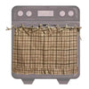 A rustic plaid fabric skirt cover draped over the door of a gray oven.