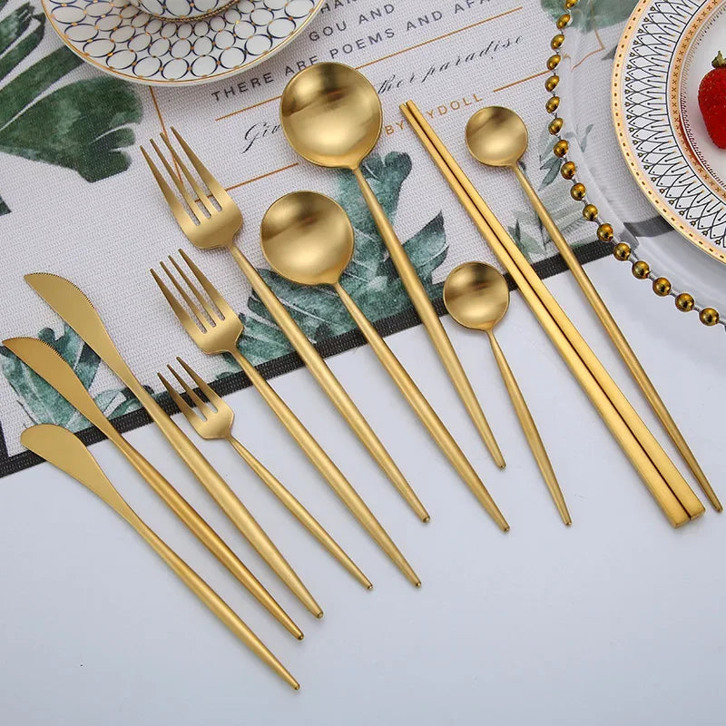A set of matte gold stainless steel cutlery including forks, spoons, and knives arranged on a white surface.