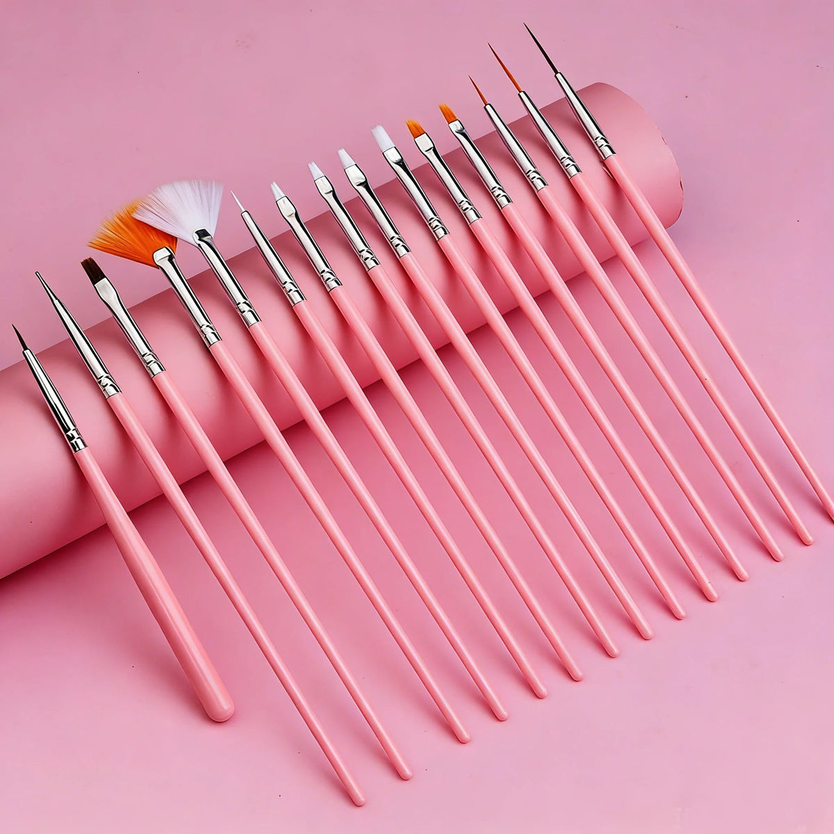 A collection of pink professional nail art brushes with various tips and a brush, arranged diagonally on a pink background.