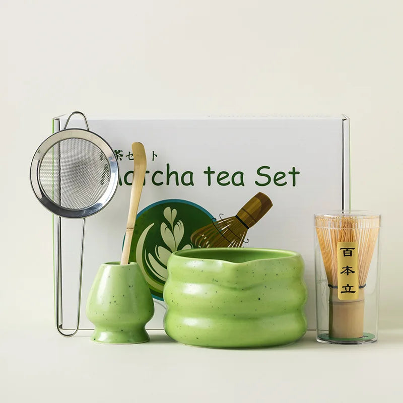 A green matcha tea set featuring a ceramic bowl, whisk, and strainer displayed on a white background.