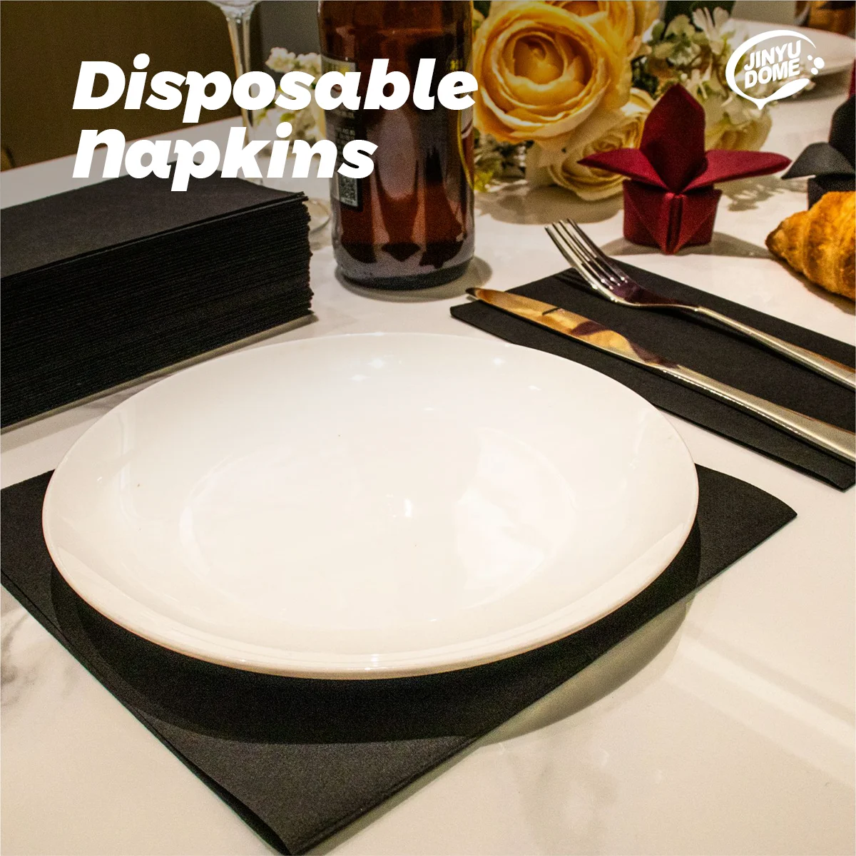 A white dinner plate is placed on a black napkin on a white marble table with a glass and a red fabric accent.