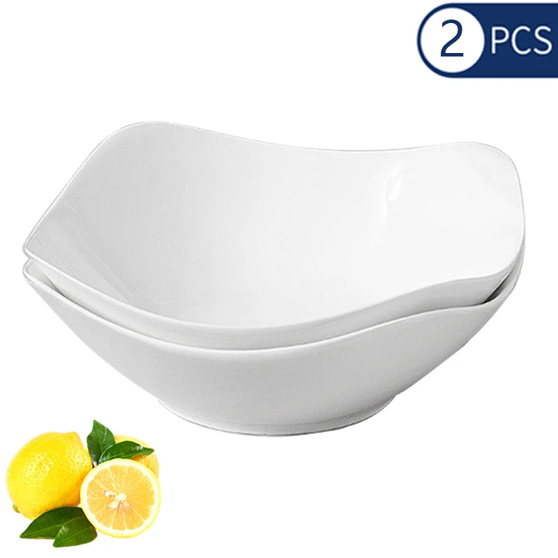 A set of two white reusable PP salad bowls shown with a lemon for scale.