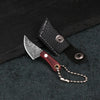 A black leather sheath holds a small Damascus pattern pocket knife with a wooden handle and chain.