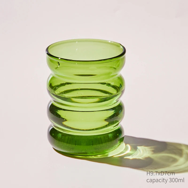 A stack of three round, translucent green glass cups or mugs.