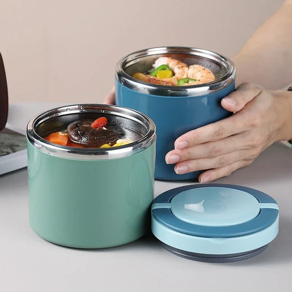 A hand holds an insulated stainless steel food jar with a lid, containing cooked shrimp and vegetables.