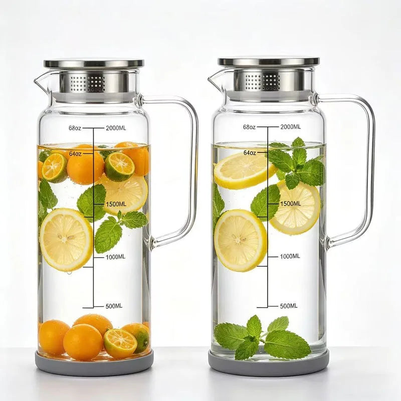 A clear glass water jug with a metal lid and measuring lines filled with citrus fruits and water.