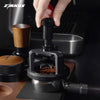 A hand is operating a black espresso stirrer needle distributor device for grinding coffee beans.