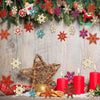 A festive arrangement of wooden snowflake ornaments in various colors and textures decorated with greenery and red accents.