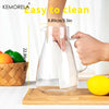 A hand is pouring water into a clear glass pitcher for beverages on a wooden cutting board.
