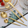 A set of matte gold stainless steel cutlery including a fork, spoon, and knife displayed on a patterned cloth.