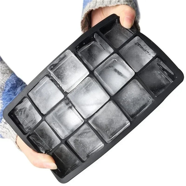 A black silicone ice cube tray with a lid is held in a hand, showing the square ice molds.