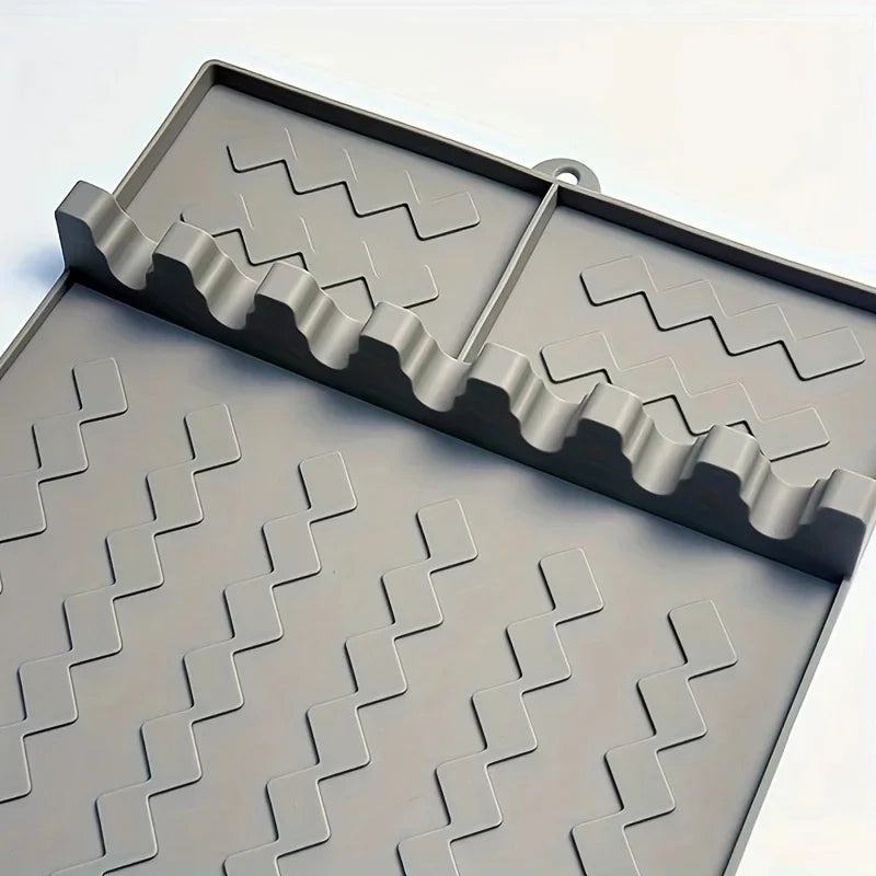 A close-up view of a gray silicone side burner rack and utensil storage mat with a slotted design.