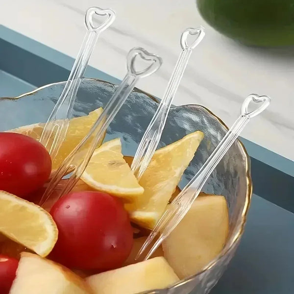 Klares Glasgefäß mit geschnittenen Äpfeln und Kirschtomaten, umgeben von eleganten Einwegpartygabeln.