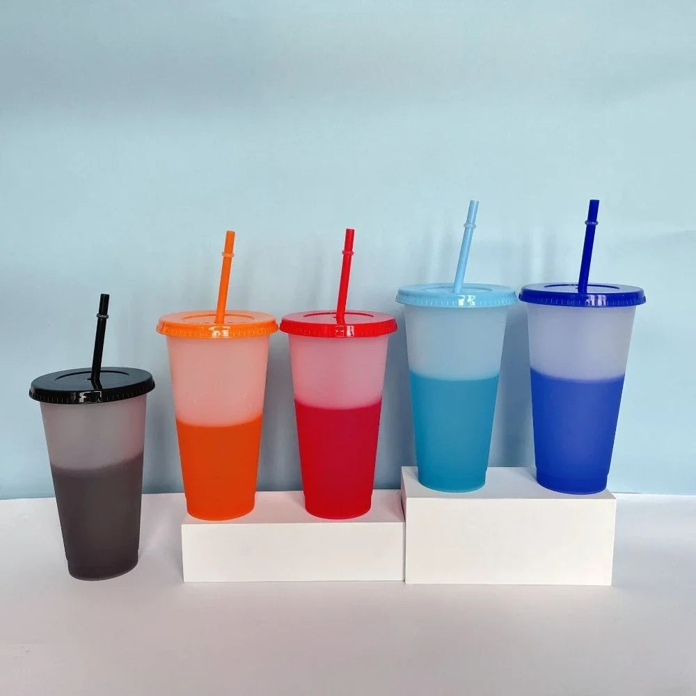 A set of five color-changing reusable tumblers in shades of orange, red, blue, and purple are displayed against a light blue 