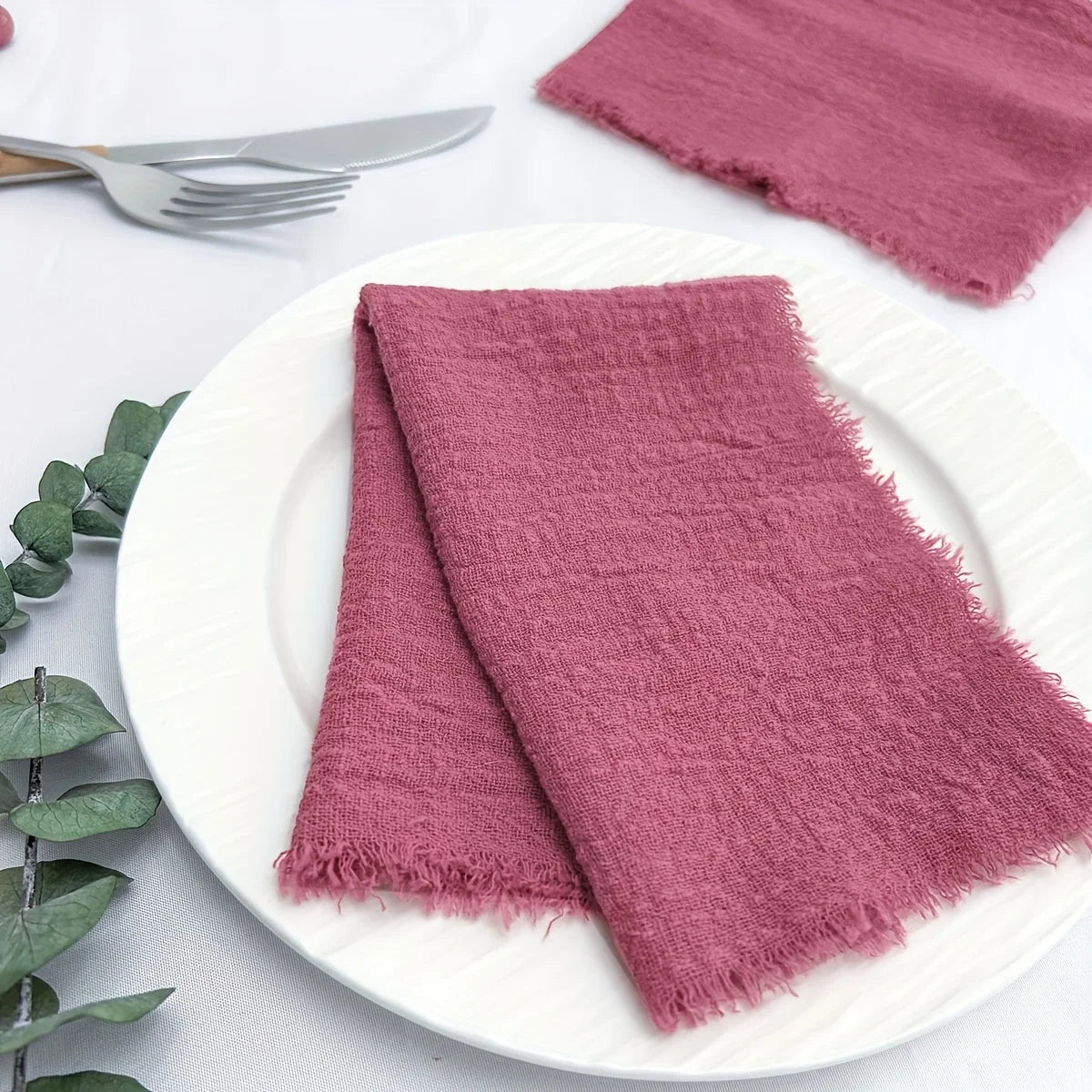 Una pila de servilletas de algodón reutilizables de color rosa intenso sobre un plato blanco.