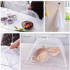 A clear mesh foldable cover protecting food and plants on a table, showing various items like fruit and bread.