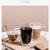 A set of clear heat resistant double wall glass drinking cups filled with dark and light brown beverages, resting on a wooden