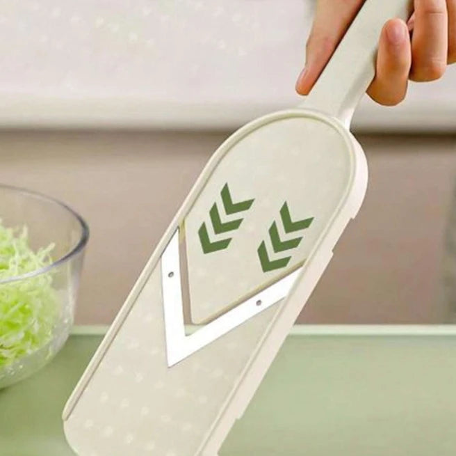 A hand holds a white multi-function vegetable slicer and grater with a green cutting blade visible.