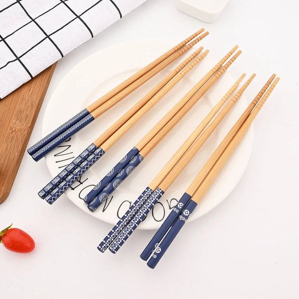 A set of reusable bamboo chopsticks with blue and white patterns resting on a white plate.