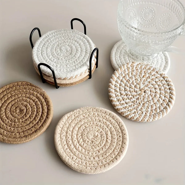 Ein Set aus vier gewebten saugfähigen Untersetzern in natürlichen Beige- und Cremetönen auf einer hellen Oberfläche.