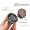 A hand holds an open reusable coffee capsule with a rubber ring and a precision filter inside.