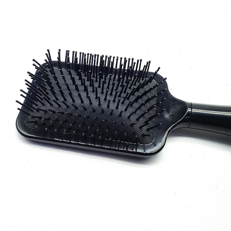 A black hair brush with numerous fine bristles is shown against a white background.