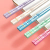A set of reusable multi-color chopsticks in lavender, beige, blue, and mint green are displayed on a light surface.