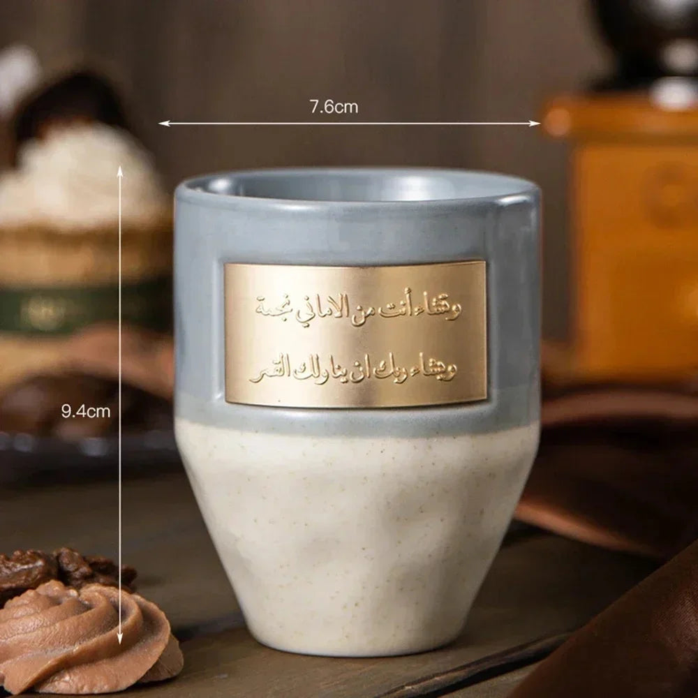 كوب خزفي أزرق فاتح مع نقش ذهبي موضوع على سطح خشبي.