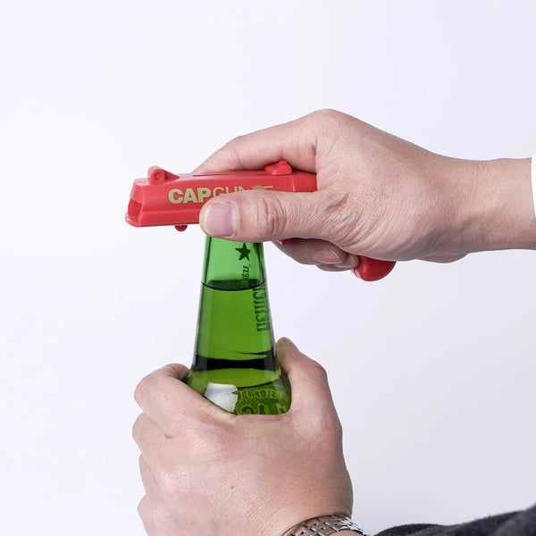 Eine Hand hält einen roten Flaschenöffner über eine grüne Glasflasche.