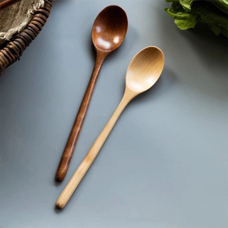 A set of two wooden spoons, one dark brown and one light wood, are placed on a gray surface.