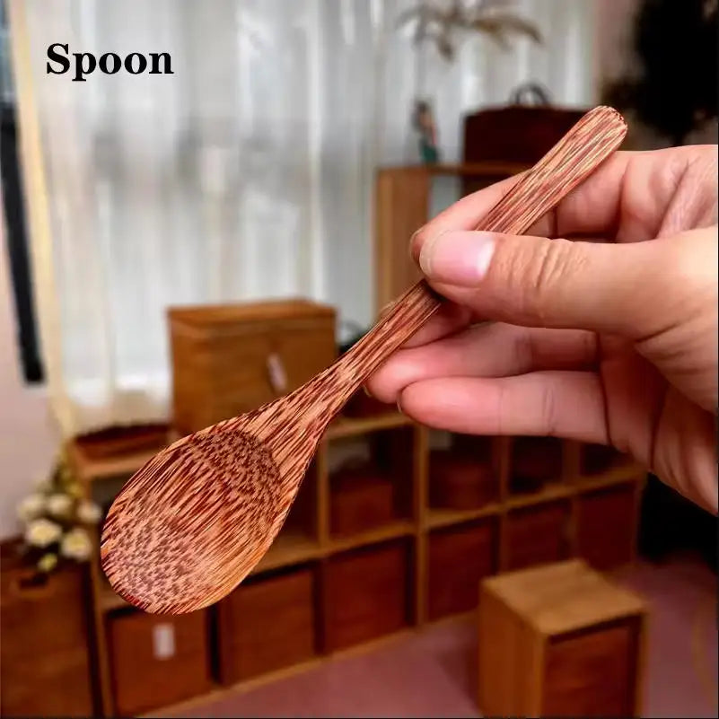 A hand holds a wooden spoon with a reddish-brown finish against a blurred background.