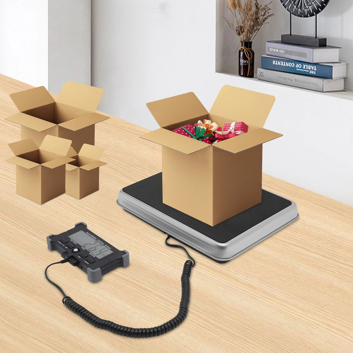 A digital shipping scale with a black cord is placed on a cardboard box on a wooden surface.