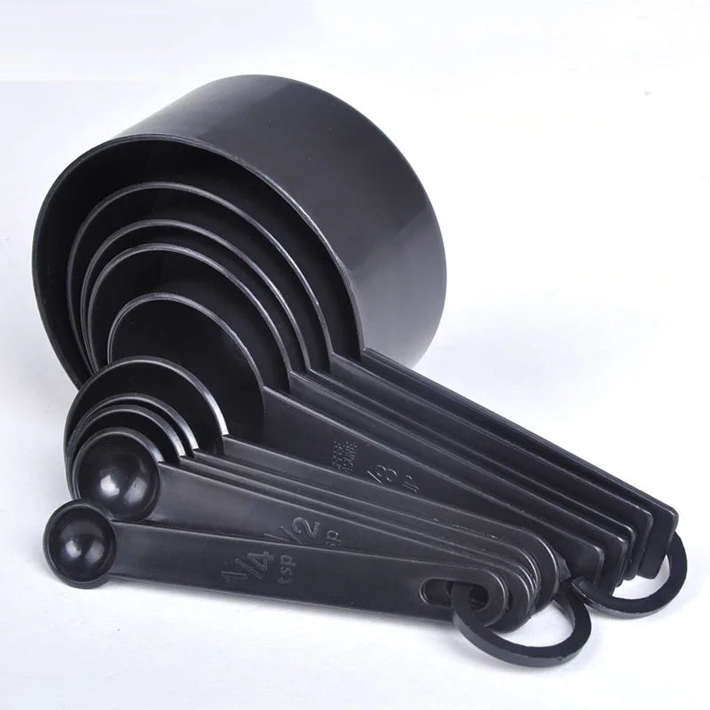A black precision kitchen measuring tools set with multiple graduated cups and a hinged handle.