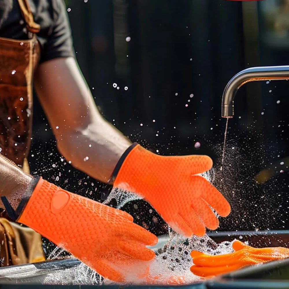 A person wearing bright orange silicone oven gloves is using a faucet to spray water onto food or equipment.