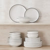 A display of white porcelain dinnerware including plates and bowls on a wooden shelf.