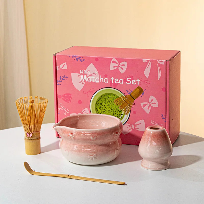 A pink box containing a Japanese matcha tea set with a ceramic bowl and whisk on a white surface.