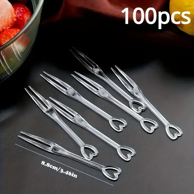 مجموعة من 100 شوكة حفل شفافة يمكن التخلص منها موضوعة على سطح داكن.